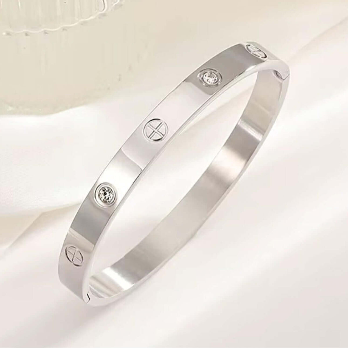 Silver stainless steel cuff bracelet with zirconia stones shown next to a hand for scale