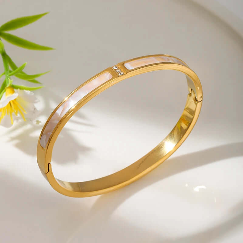 Gold bracelet with pink stones on a light background