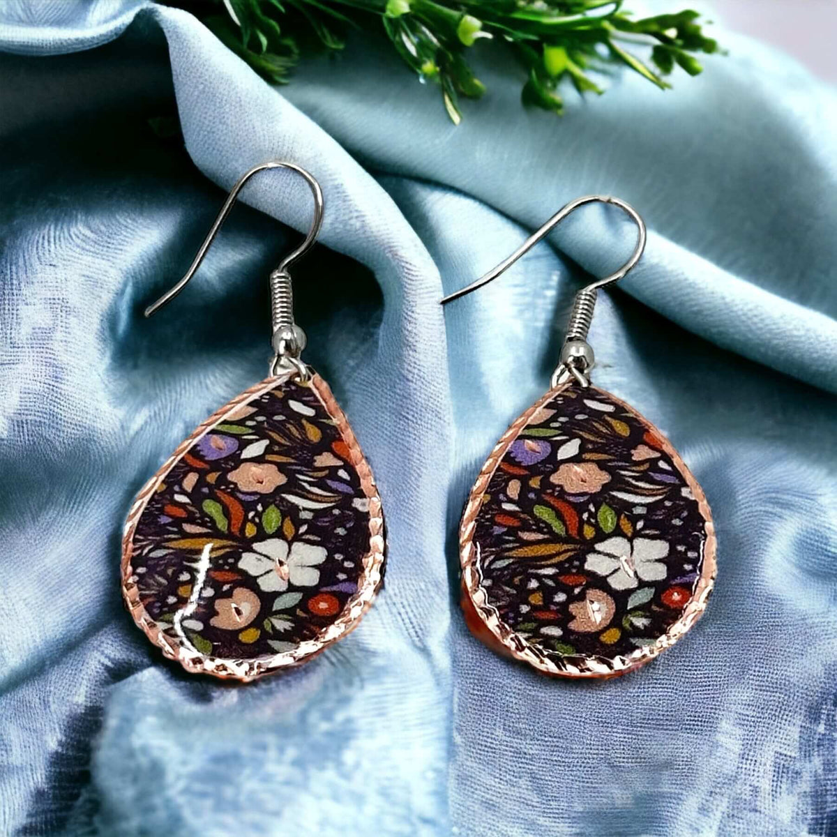 Three-piece purple and white flowers copper jewellery set shown next to a hand for scale