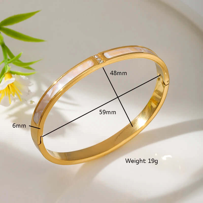 Gold bracelet with measurements and weight on a light background