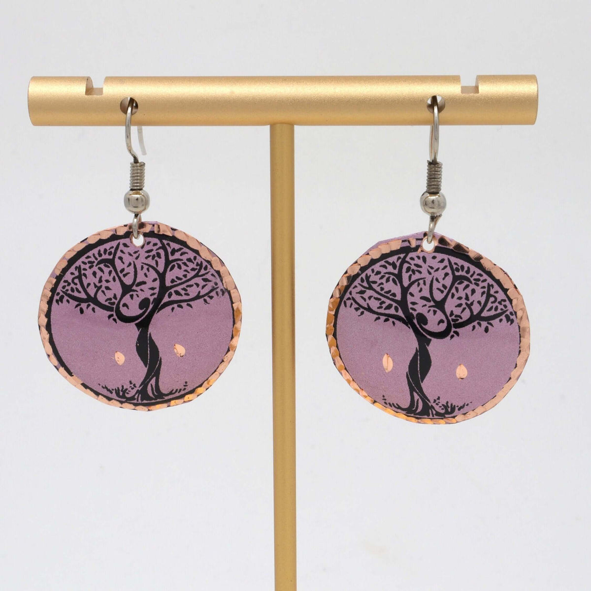 A pair of handcrafted lavender tree copper circle earrings laid flat