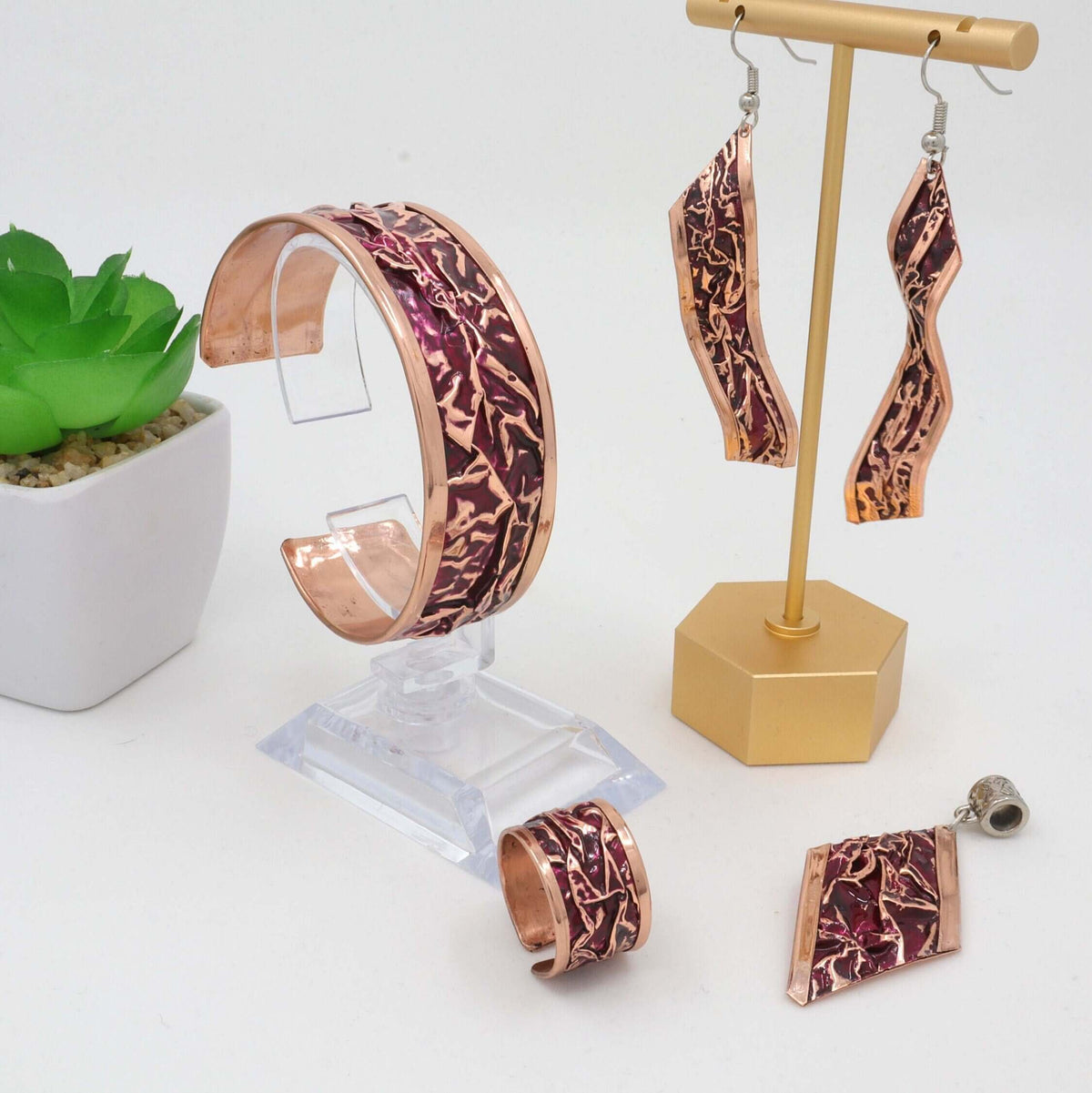 Individual pieces from handcrafted magenta wrinkled copper jewellery set arranged together