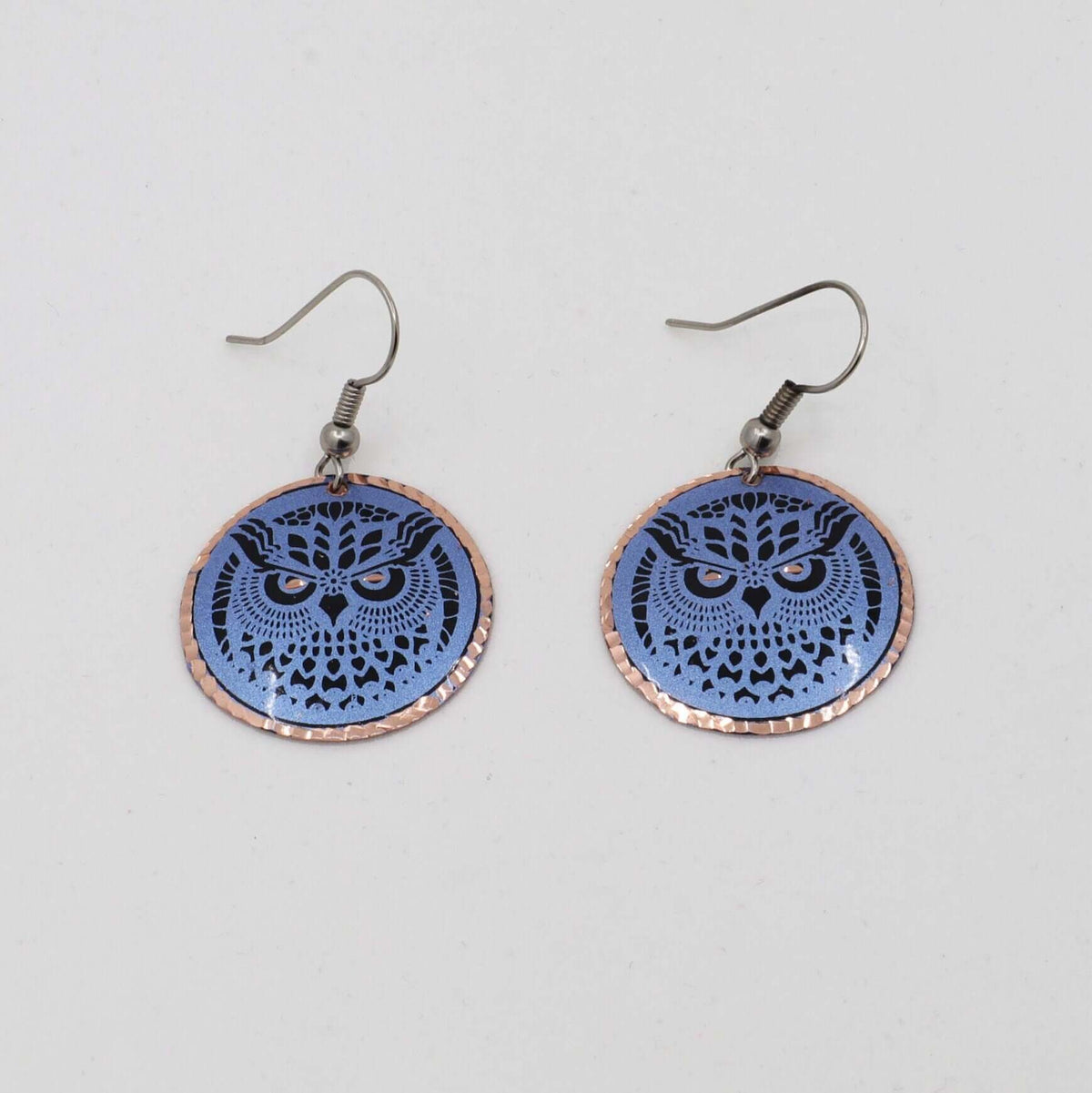 Handcrafted blue owl copper circle earrings shown next to a hand for scale