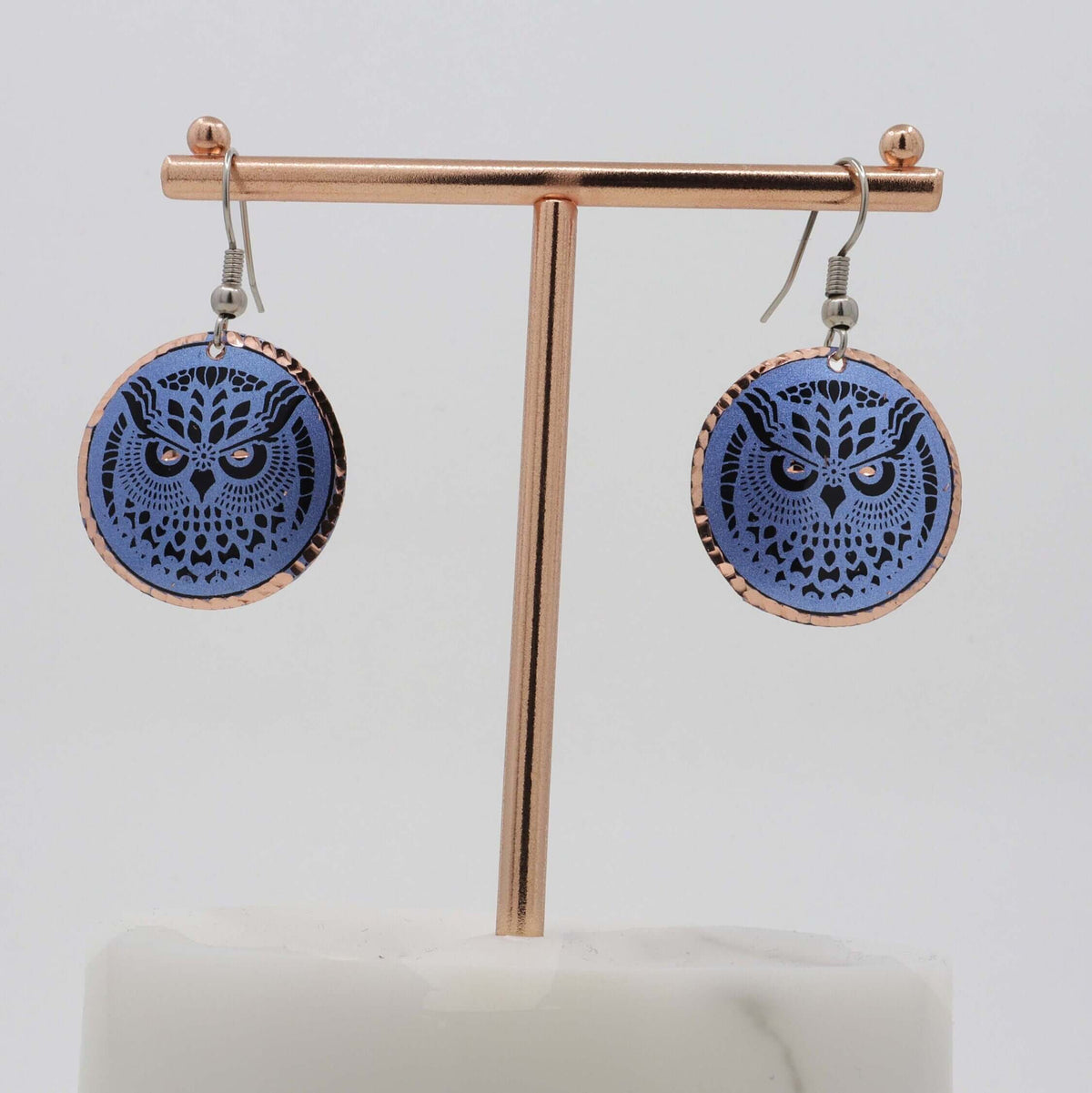 Top-down view of handcrafted blue owl copper circle earrings