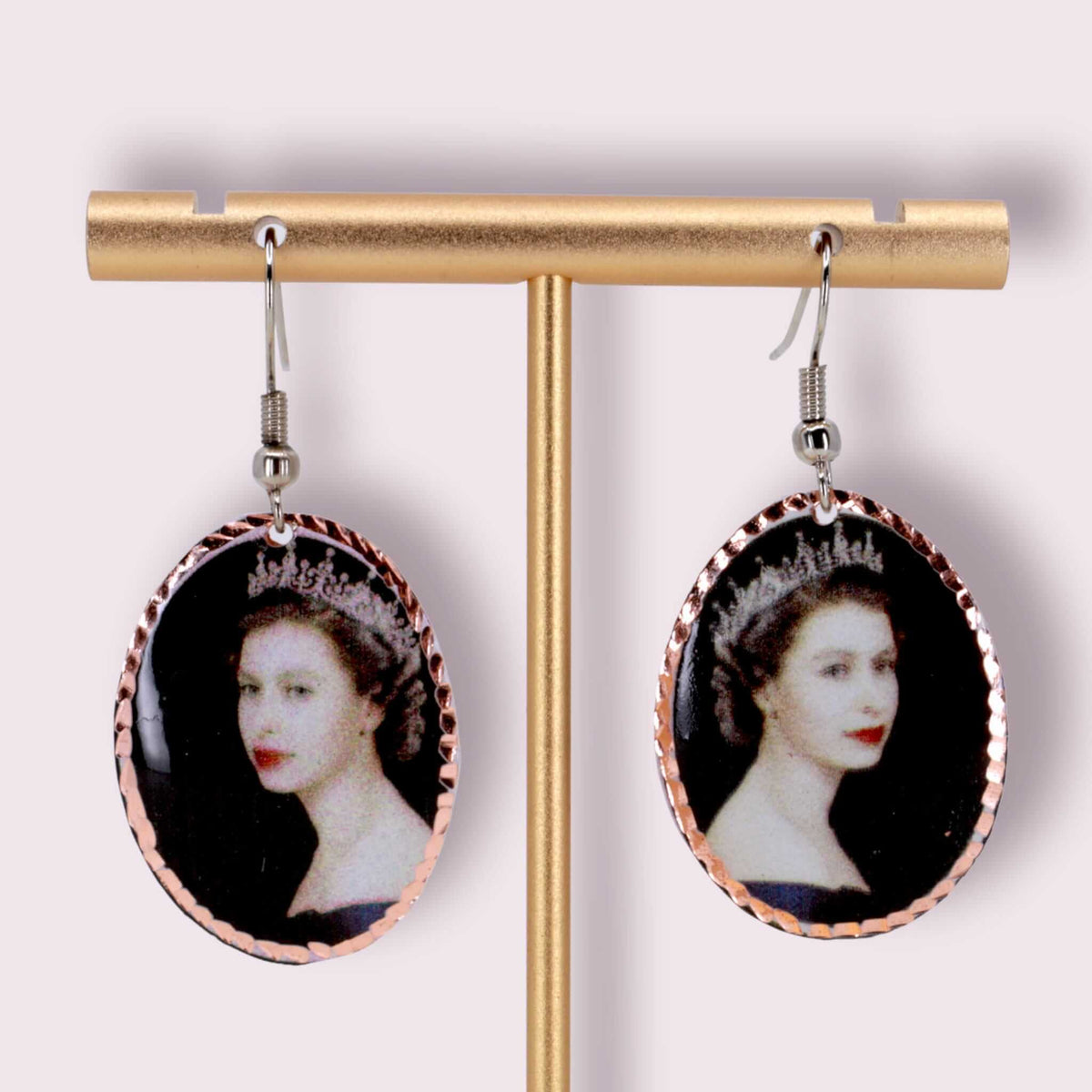 A pair of artisan Queen Elizabeth II copper oval earrings laid flat