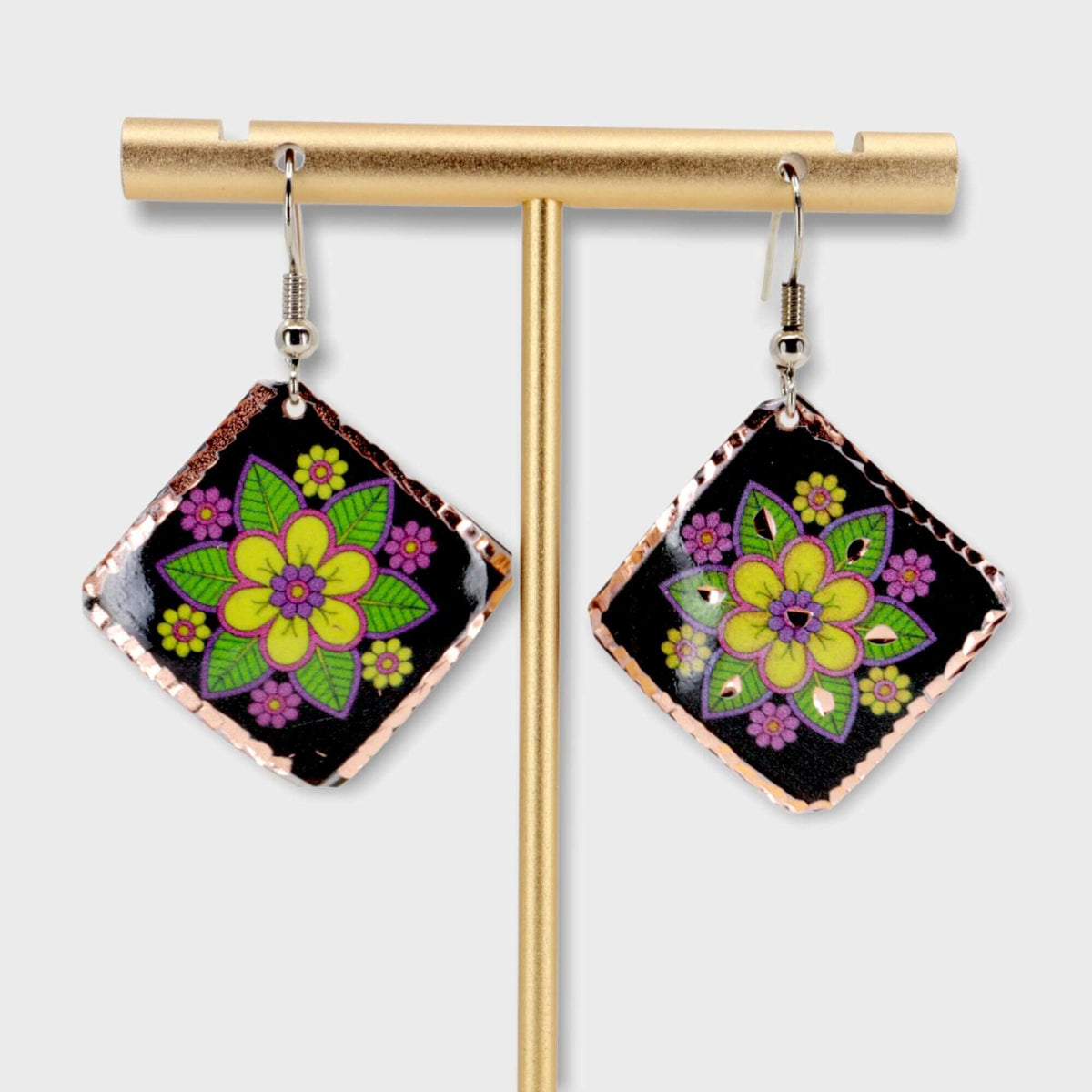 A pair of handcrafted square yellow flower copper earrings laid flat