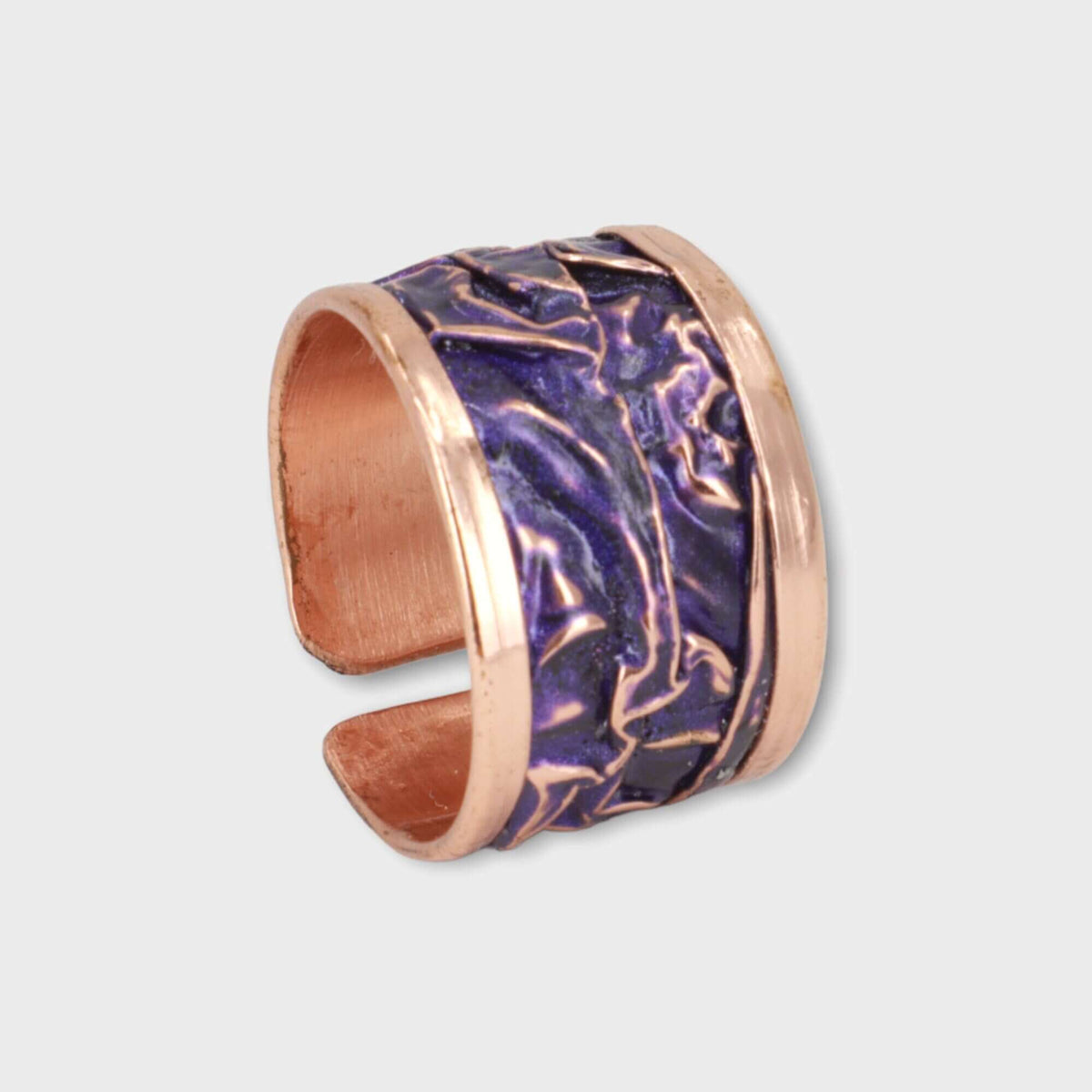 Purple wrinkled copper adjustable ring shown next to a hand for scale