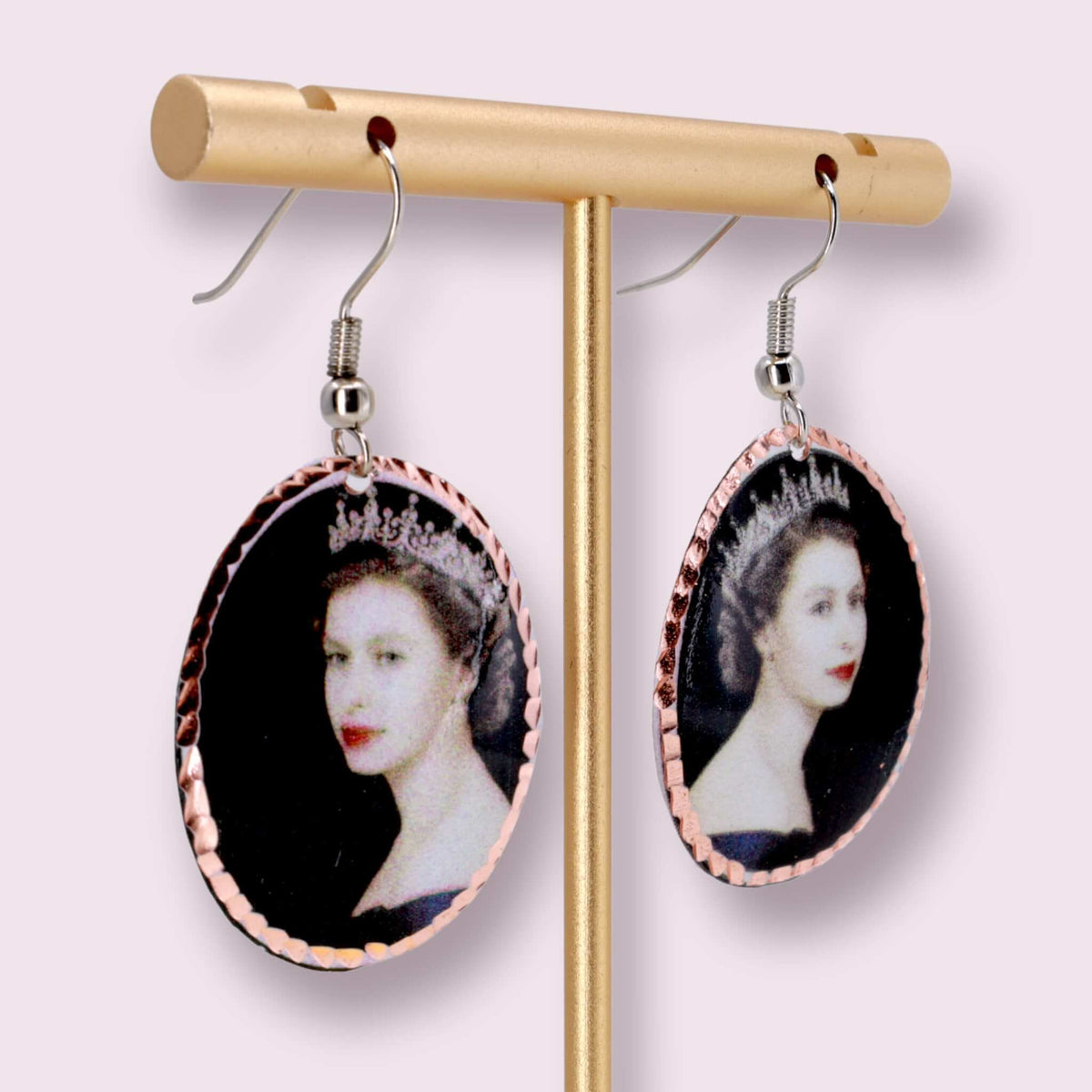 Artisan Queen Elizabeth II copper oval earrings shown next to a hand for scale