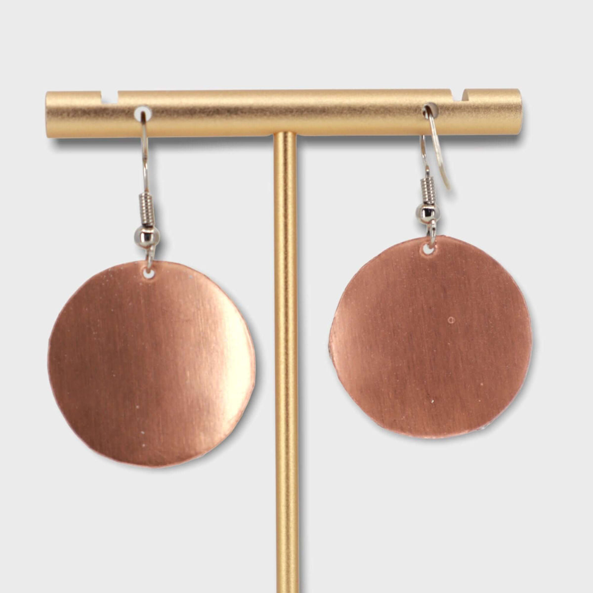 Handcrafted butterfly copper circle earrings shown next to a hand for scale