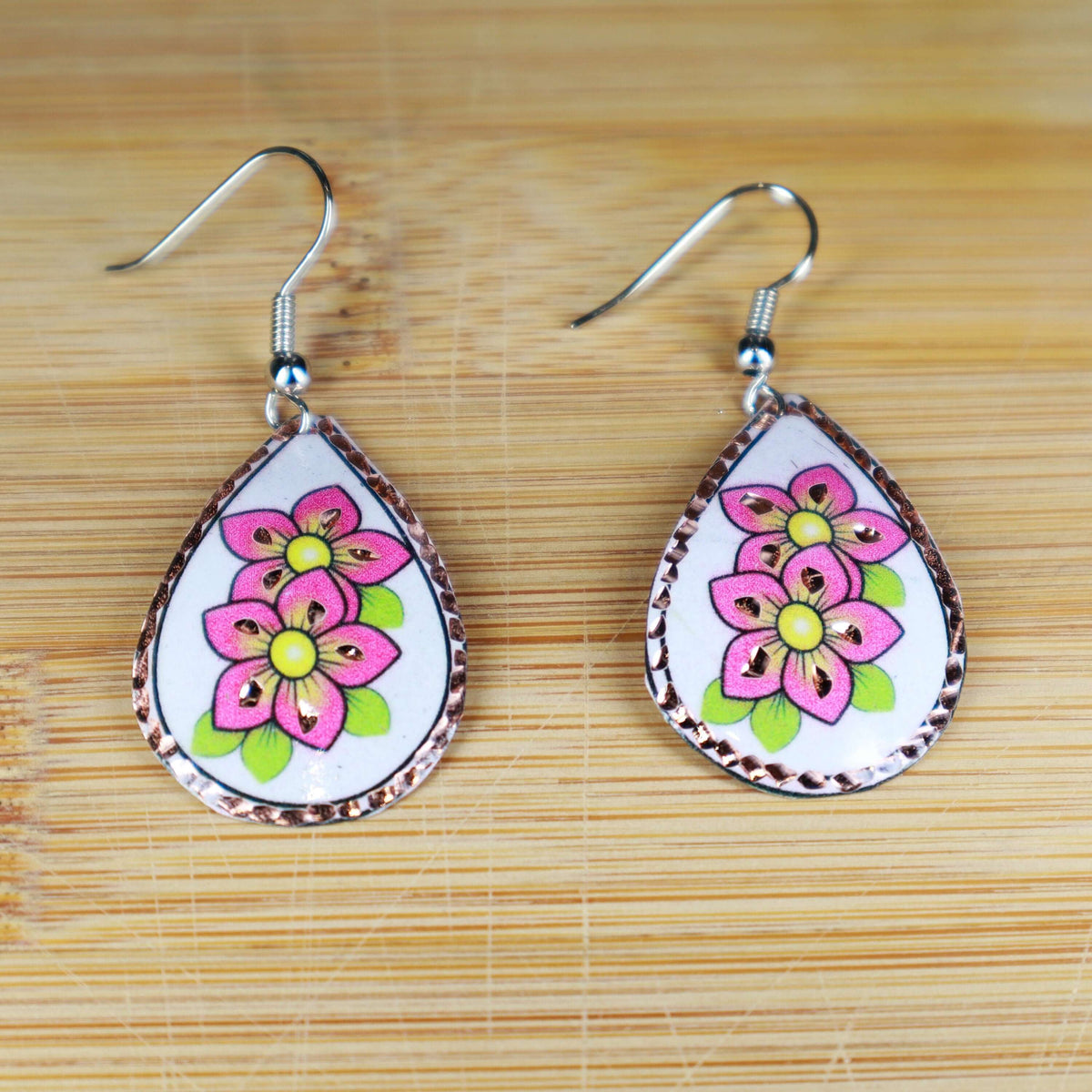 Handcrafted pink flower copper drop earrings displayed on a plain background